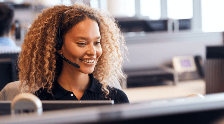 A woman sat at a computer wearing a telephone headset